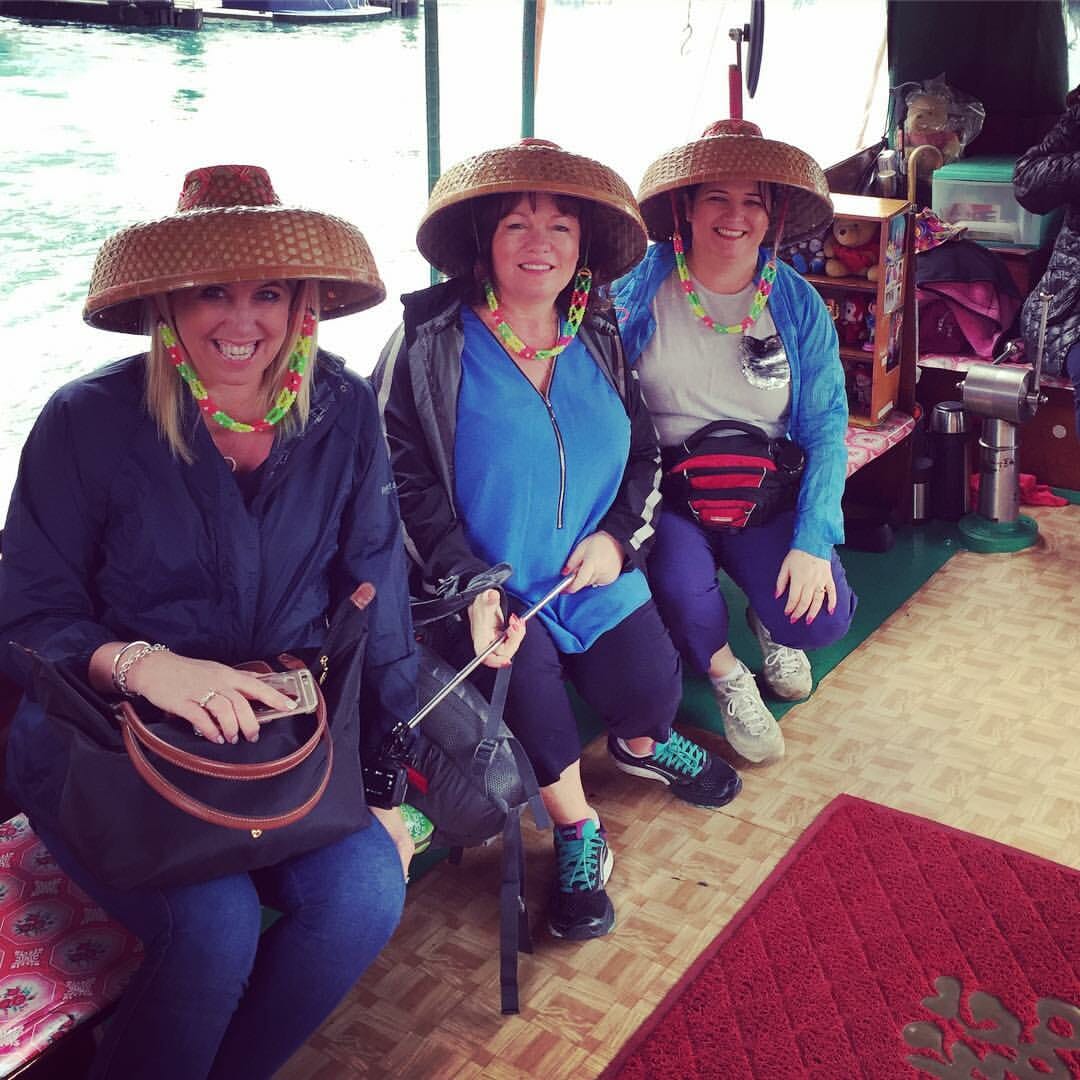 ladies on sampan ride wearing tanka hats enjoying a private hong kong tour