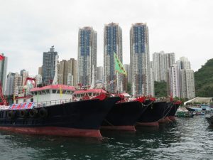 Boats in Aberdeen Hong Kong with skycrapers in the background.