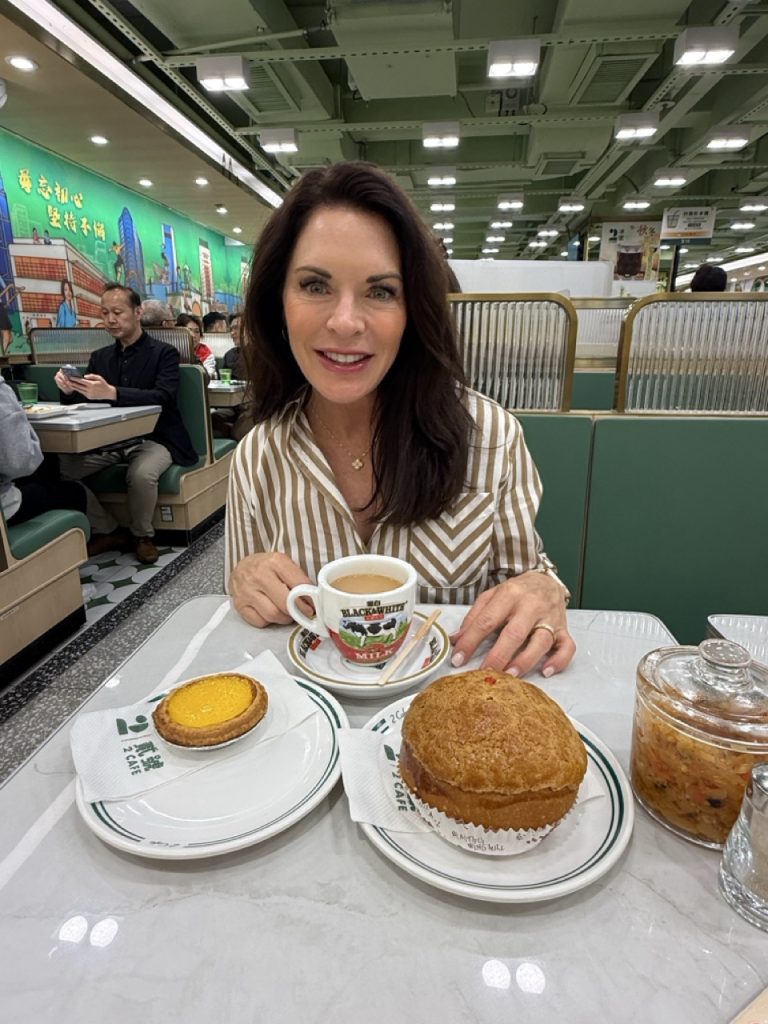 Cruise guest trying an egg tart and pineapple bun at a Hong Kong cha chaan teng